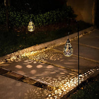Solarbetriebene Gartenleuchte, tropfenförmig, schwarz-gold, beleuchtet Gehweg nachts.