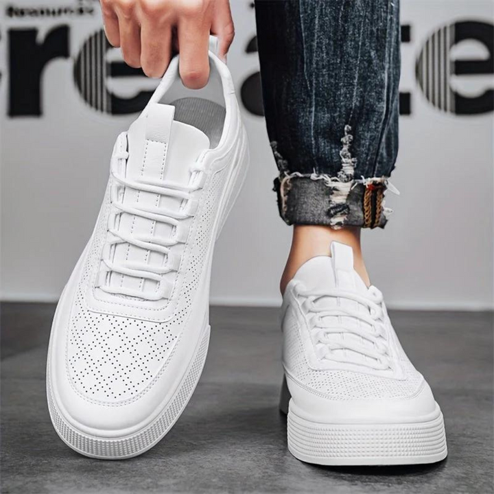 Weiße Sneaker aus Leder, perforiert, modisch, unisex, lässig, mit Jeans kombiniert.