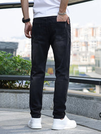 Mann in schwarzer Jeans und weißen Sneakers, Rückansicht, urbaner Hintergrund.