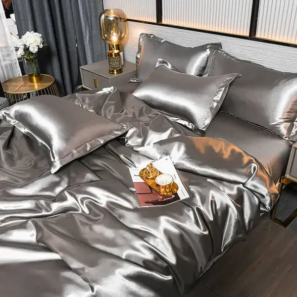 Graues Seidenbettwäsche-Set, luxuriös, glänzend, mit Kissenbezügen und Nachttischlampe.