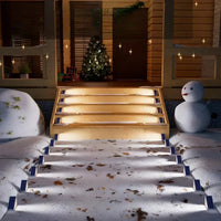 Beleuchtete Außentreppe mit Schneemann und Weihnachtsbaum, winterliche Dekoration, Nachtansicht.