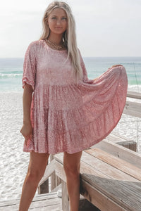 Frau in rosa Paillettenkleid am Strand, Sommermode, elegantes Freizeitoutfit, Meereshintergrund.