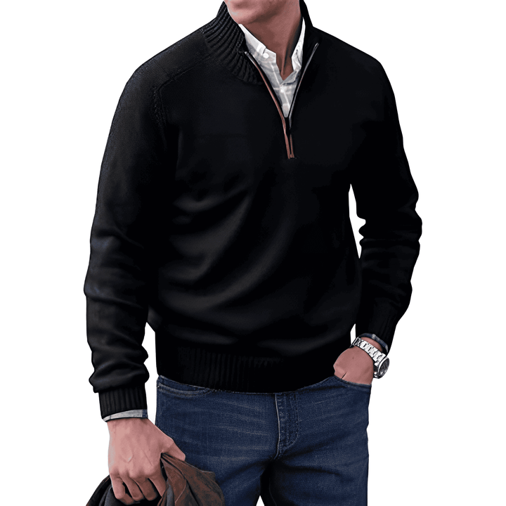 Mann in schwarzem Pullover mit Reißverschluss, blaue Jeans, hält braune Jacke, modisch, lässig.