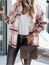 Frau mit rosa kariertem Hemd, weißem T-Shirt, schwarzer Tasche, Jeans, Uhr, Smartphone.