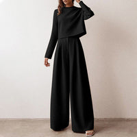 Frau in elegantem schwarzen Anzug, weite Hose, langärmeliges Oberteil, modisch, minimalistisch.