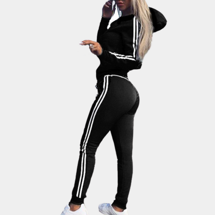 Frau in schwarzem Trainingsanzug mit weißen Streifen, Kapuze, sportlich, modisch, Freizeitkleidung.