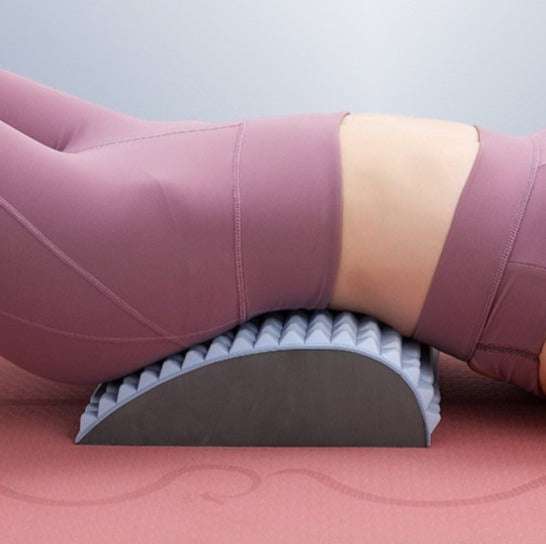 Frau in rosa Sportkleidung auf grauem Schaumstoff-Rückenstrecker, Yoga-Übung, Fitnessgerät.