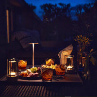 Abendliche Tischdekoration mit Kerzen, Getränken und Snacks im Freien bei Dämmerung.