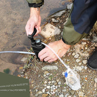 Mann pumpt Wasser mit tragbarem Wasserfilter, Outdoor-Camping, schwarz, effizient, kompakt.