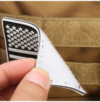 Hand hält USA-Flaggen-Patch mit Klettverschluss auf brauner taktischer Tasche.