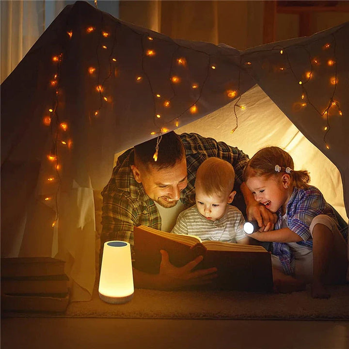 Vater liest Kindern im Zelt vor, umgeben von Lichterketten, gemütliche Familienzeit.
