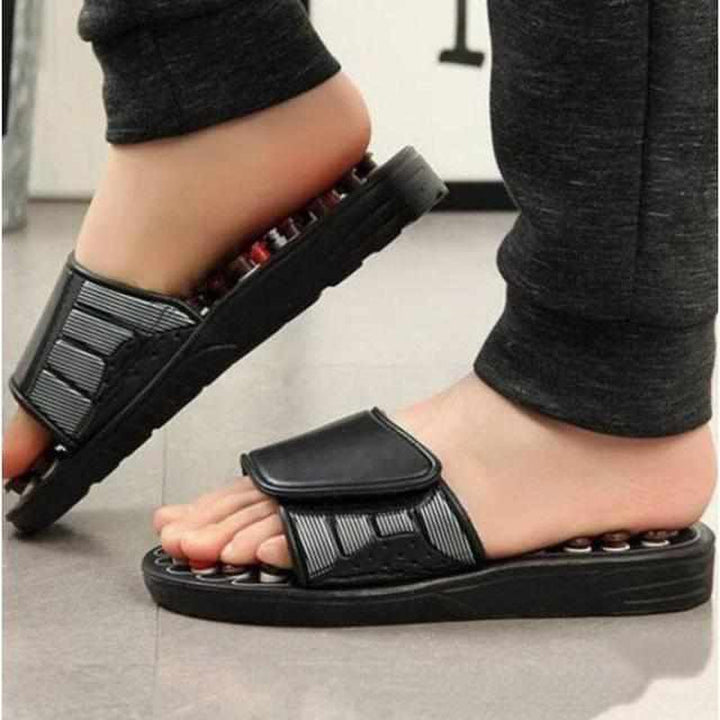 Schwarze Akupressur-Sandalen mit Massagefunktion, getragen von Person, Nahaufnahme.