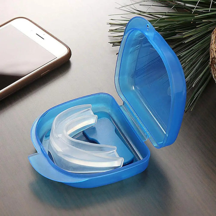 Blaue Zahnschiene im Etui, Anti-Schnarch-Gerät, Kunststoff, auf Tisch neben Smartphone.