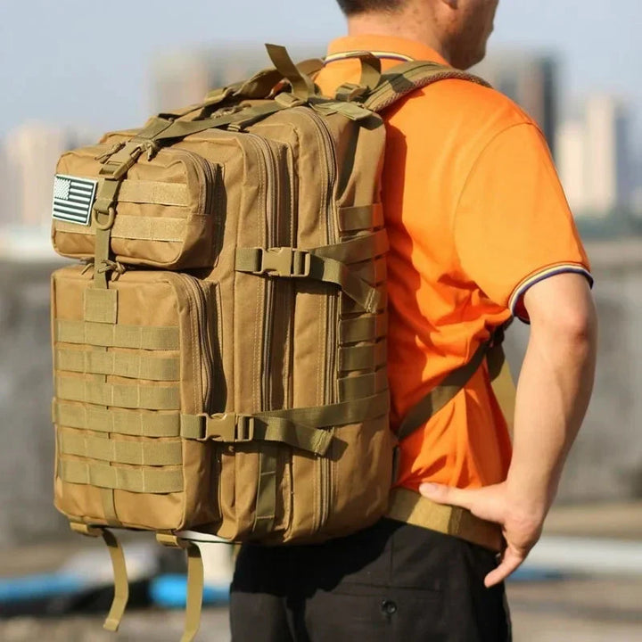Mann mit großem, braunem taktischem Rucksack im Freien, ideal für Outdoor-Abenteuer.