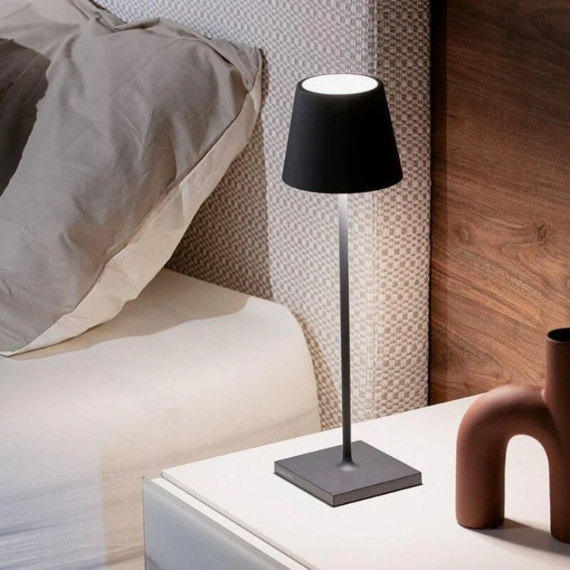 Schwarze Tischlampe auf Nachttisch neben Bett, modernes Design, Schlafzimmerbeleuchtung.