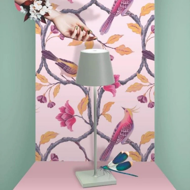 Graue Tischlampe vor rosa Tapete mit Vögeln und Blumen, modernes Innendesign.