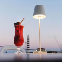 Rotes Cocktailglas und weiße Tischlampe bei Sonnenuntergang, stilvolle Outdoor-Dekoration.