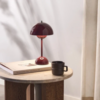 Rote Tischlampe auf Holztisch mit Buch und schwarzer Tasse, modernes Innendesign, Wohnzimmer.