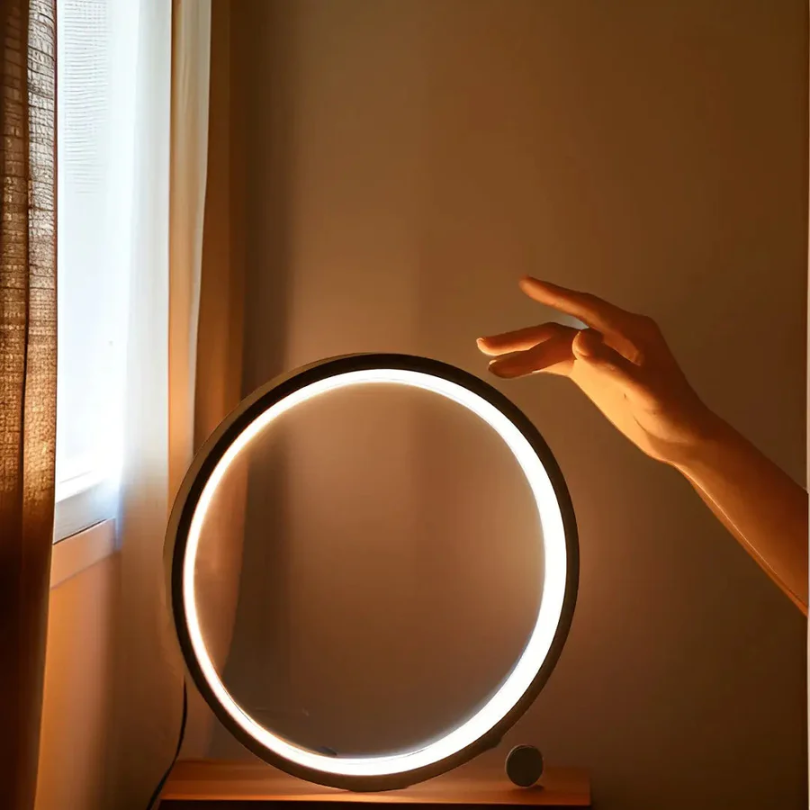 Runder LED-Ringlicht auf Tisch, Hand berührt Licht, modernes Design, warmes Leuchten.