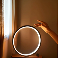 Runder LED-Ringlicht auf Tisch, Hand berührt Licht, modernes Design, warmes Leuchten.