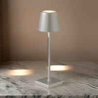 Moderne silberne Tischlampe aus Metall auf Marmortisch, minimalistisch, LED-Beleuchtung.