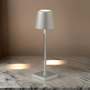 Moderne silberne Tischlampe aus Metall auf Marmortisch, minimalistisch, LED-Beleuchtung.