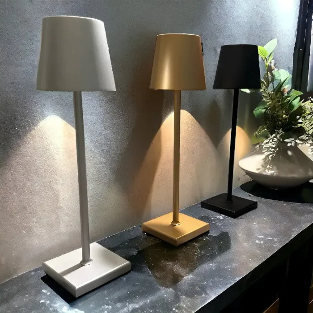 Drei moderne Tischlampen in Weiß, Gold und Schwarz auf dunklem Tisch, minimalistisch, LED-Beleuchtung.