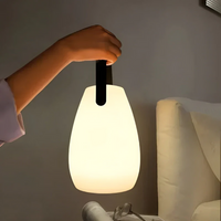 Tragbare LED-Lampe, weiß, mit schwarzem Griff, ideal für Schlafzimmerbeleuchtung.