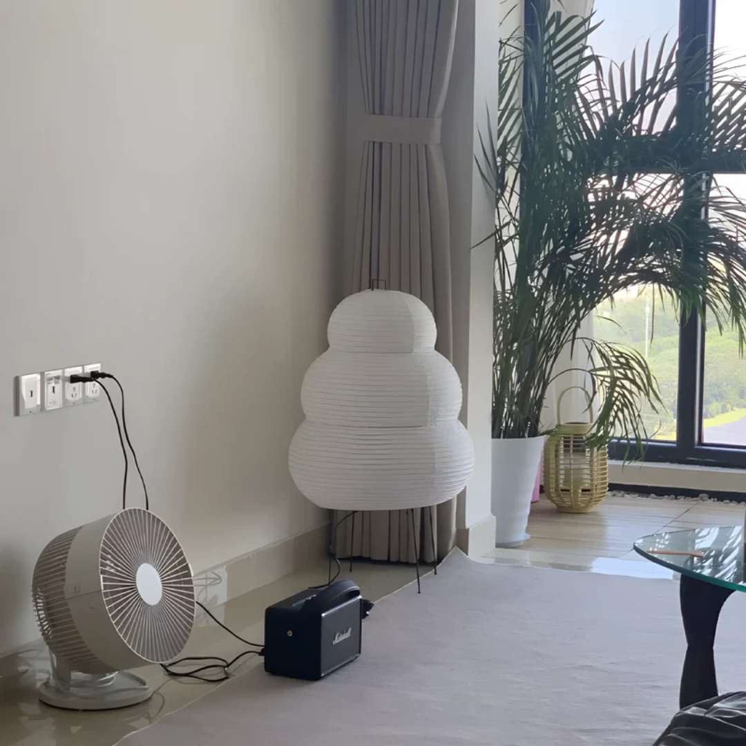 Weißer Papierlampenschirm, Ventilator und Lautsprecher in modernem Wohnzimmer mit großen Fenstern.