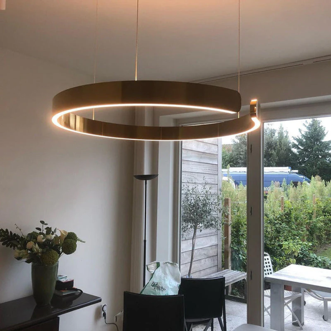 Moderne runde LED-Hängelampe in Gold über Esstisch, minimalistisches Design, Innenbeleuchtung.