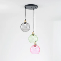 Moderne dreifarbige Pendelleuchte mit Glaslampenschirmen in Schwarz, Grün und Rosa.