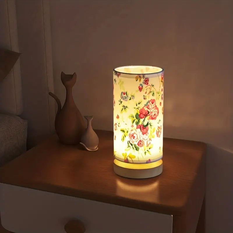 Blumenmuster Tischlampe, zylindrisch, beleuchtet, auf Holztisch, Schlafzimmerdekoration.