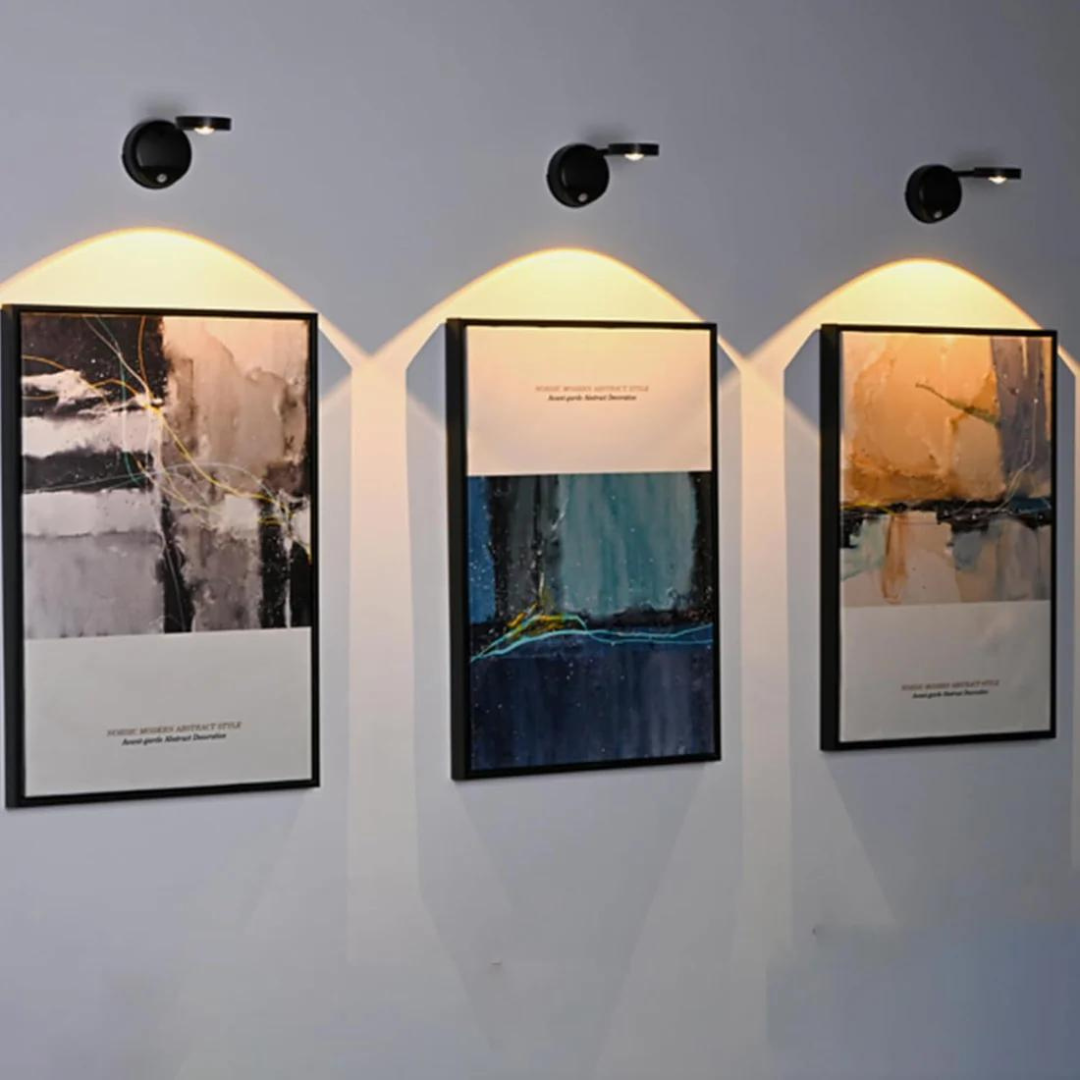 Drei moderne abstrakte Gemälde mit Beleuchtung an grauer Wand, Kunstdekoration Wohnzimmer.