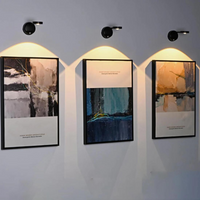Drei moderne abstrakte Gemälde mit Beleuchtung an grauer Wand, Kunstdekoration Wohnzimmer.