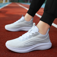 Weiße Sportschuhe auf roter Laufbahn, atmungsaktiv, ideal für Laufen und Fitness.