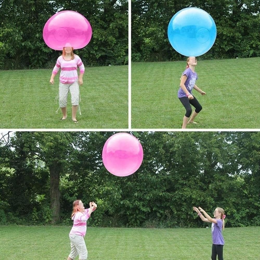 Personen spielen mit großen, bunten Luftblasenbällen im Freien auf einer Wiese.