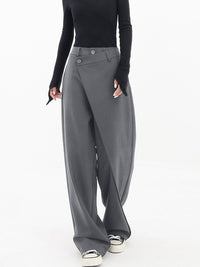 Frau trägt graue asymmetrische Baggy-Hose, modisch, elegant, mit schwarzem Oberteil.