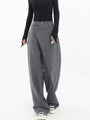 Frau trägt graue asymmetrische Baggy-Hose, modisch, elegant, mit schwarzem Oberteil.