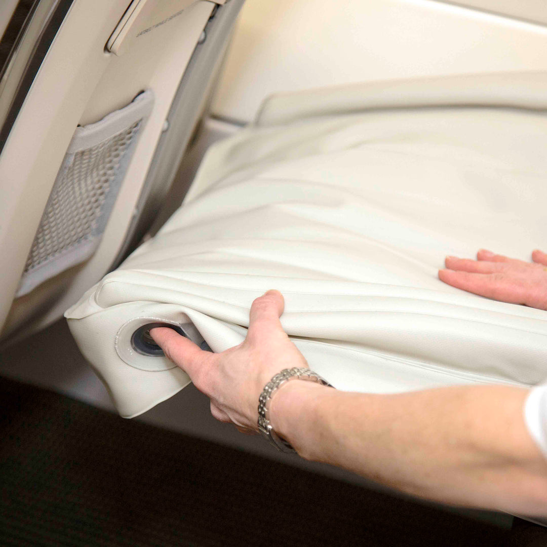 Person entleert aufblasbares Kinderbett im Flugzeug, beige, Reiseaccessoire, Komfort.