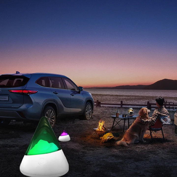 Blauer SUV am Strand bei Sonnenuntergang, Camping mit Hund und tragbarer LED-Lampe.
