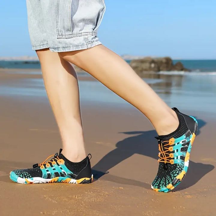 Person trägt bunte Wasserschuhe am Strand, ideal für Outdoor-Aktivitäten und Wassersport.