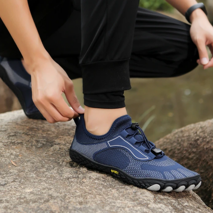 Dunkelblauer Barfußschuh auf Felsen, atmungsaktiv, sportlich, ideal für Outdoor-Aktivitäten.