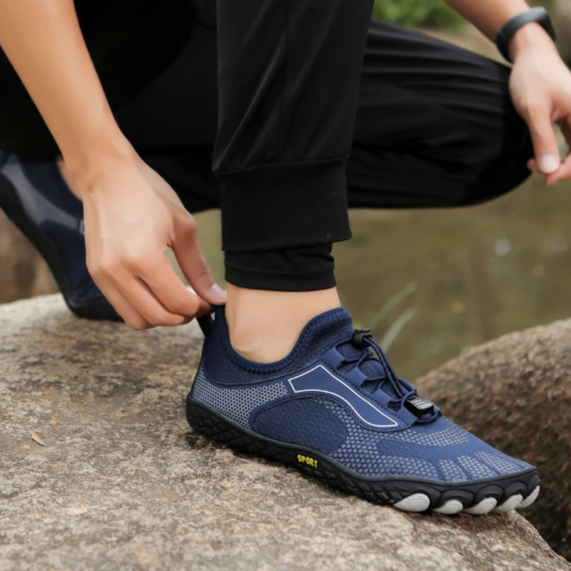 Dunkelblauer Barfußschuh auf Felsen, atmungsaktiv, sportlich, ideal für Outdoor-Aktivitäten.