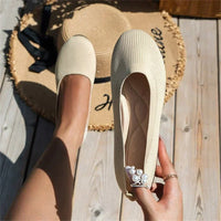 Beige Damen-Ballerinas aus Strickstoff, flach, mit Perlendetail, auf Holzterrasse.