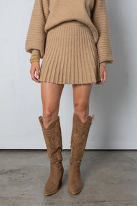Frau in beigem Strickkleid und Stiefeln, modisches Herbstoutfit, gemütlicher Look.