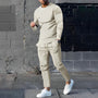 Mann in beigem Trainingsanzug, weiße Sneaker, graue Wand, urbane Mode, Streetwear-Look.