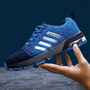 Blaue Laufschuhe mit weißen Streifen, atmungsaktiv, sportlich, für Herren, auf grauem Boden.