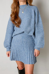 Frau in blauem Strickpullover und Faltenrock, Herbstmode, gemütlicher Look, Damenbekleidung.