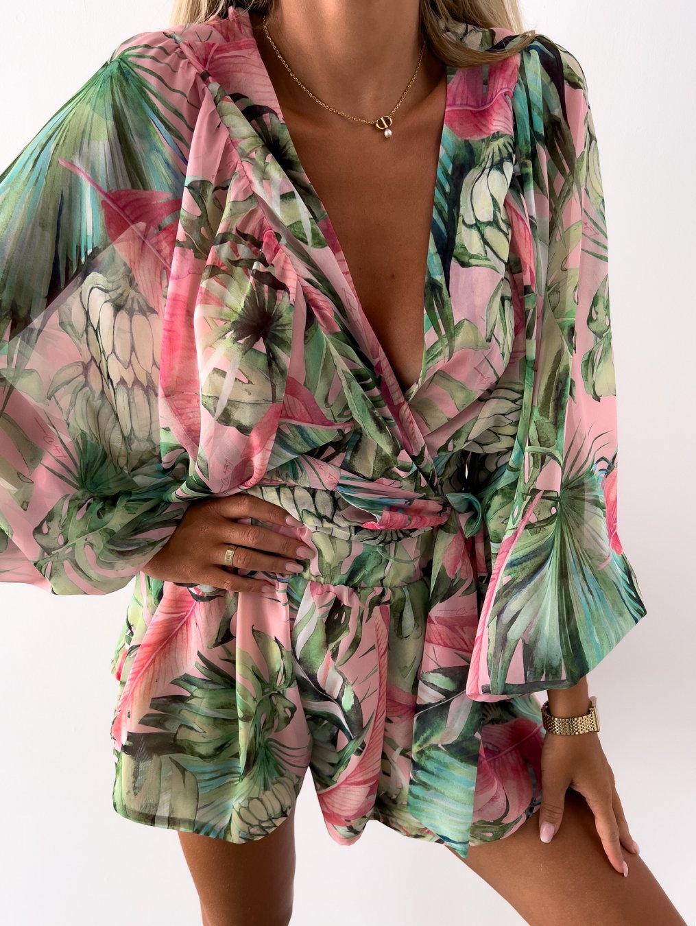 Frau in grün-rosa geblümtem Sommerkleid mit V-Ausschnitt und langen Ärmeln.
