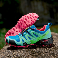 Blauer und grüner Trailrunning-Schuh mit pinker Sohle auf Felsen, ideal für Outdoor-Sport.